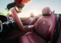 Close-up of the front seats and interior of a luxury convertible featuring quilted red leather, part of the BRABUS Rocket GTC Deep Red that breaks cover at Pebble Beach with 1000 HP and an all-carbon body. Sunlight streams in, highlighting every detail.