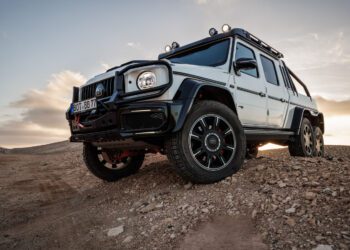 A BRABUS XLP 800 6x6 ADVENTURE Mercedes-Benz G-Class off-road vehicle is parked on rocky terrain at sunset.