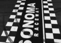 Black and white photo of the Sonoma Raceway finish line with a blurred race car crossing and large "SONOMA RACEWAY" text on the track.
