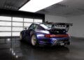 An exclusive blue Gunther Werks GWX, inspired by Porsche 911 remastering, sits parked in a modern, well-lit garage with a polished concrete floor and a prominent rear wing.
