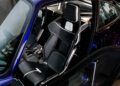 Close-up view of the interior of a Gunther Werks Porsche 911, showcasing two black racing-style bucket seats with carbon fiber accents and white trim—a testament to the brand’s artful remastering of classic sports car design.