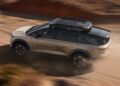 A silver and black SUV labeled "GRAVIT" drives on a dusty, unpaved road, echoing the Pebble Beach Debut: Rugged Lucid Gravity X Concept Breaks Cover With 828 HP & Trail-Ready Upgrades as it kicks up dirt behind its tires.