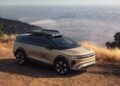 A beige SUV with "GRAVIT" branding is parked on a dirt road overlooking a scenic, foggy valley and distant mountains—echoing the Pebble Beach Debut: Rugged Lucid Gravity X Concept breaks cover with 828 HP & trail-ready upgrades.