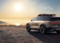 A silver SUV with "GRAVITY" on the side is parked on a dirt path at sunset, showcasing its Pebble Beach debut as the rugged Lucid Gravity X Concept with 828 HP, trail-ready upgrades, roof rack, and large rear taillights.