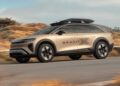 A modern SUV labeled "GRAVIT" drives on a paved road with dry vegetation in the background. Inspired by the Pebble Beach Debut: Rugged Lucid Gravity X Concept, it features a roof box and sleek, aerodynamic design.