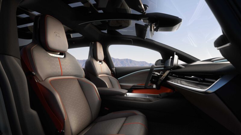 Interior view of the modern Lucid Gravity X concept, featuring two front seats, a digital dashboard, and a panoramic glass roof—unveiled at its Pebble Beach debut with 828 HP and trail-ready upgrades. Mountains are visible through the windows.