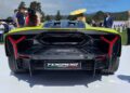 Rear view of the yellow Lamborghini Fenomeno: Limited-Run V12 Masterpiece Unveiled at Monterey, on display outdoors and surrounded by people at an automotive event.