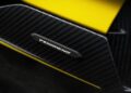 Close-up of a carbon fiber panel with a "TENOMEND" label, bordered by yellow painted surfaces—evoking the precision seen in the Lamborghini Fenomeno: Limited-Run V12 Masterpiece Unveiled at Monterey.