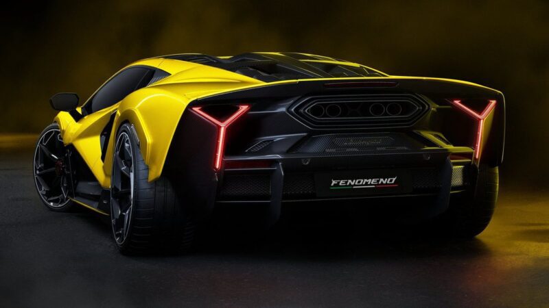A yellow and black Lamborghini Fenomeno: Limited-Run V12 Masterpiece Unveiled at Monterey is shown from the rear on a dark background, featuring angular taillights and "FENOMENO" on the license plate area.