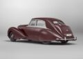 A vintage maroon Bentley with chrome trim, classic curves, and split rear windows, viewed from the back left in a studio setting—an icon reminiscent of Monterey Car Week elegance.