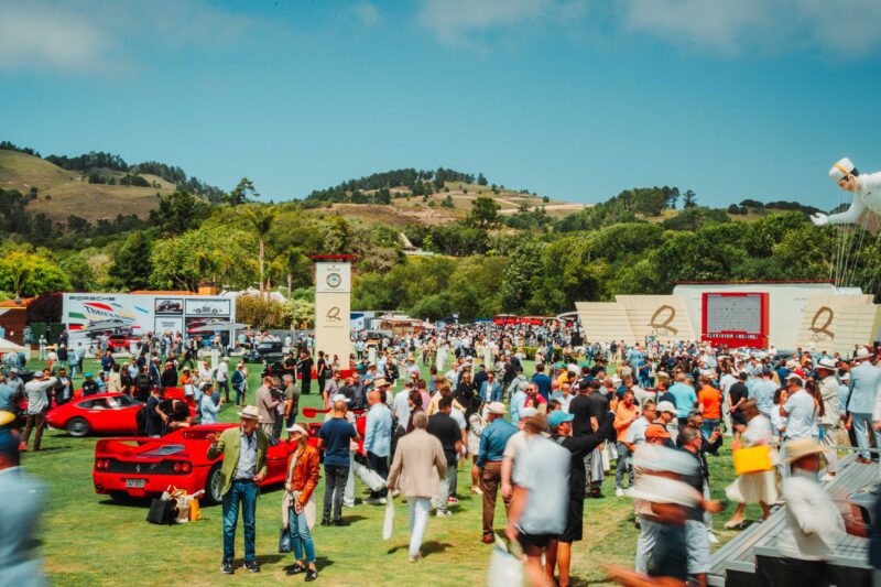 A large crowd gathers outdoors at a car show, where classic and luxury cars shine—highlighted by the Ferrari F50 GT1 crowned Best of Show at The Quail, A Motorsports Gathering 2025, all set amid hills and trees under a clear sky.