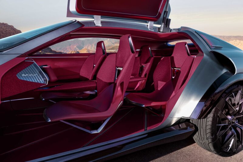 Futuristic car interior with four red seats, an open gullwing door, and a desert landscape visible in the background—Cadillac Elevated Velocity Concept Revealed: An Extreme Vision for Future Luxury EVs.