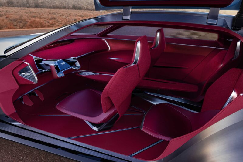Futuristic car interior with red seats, minimalist dashboard, and steering controls; gullwing door open to reveal spacious seating—an inspired vision of Cadillac Elevated Velocity in the world of luxury EVs.
