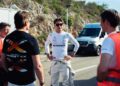 A race car driver in a white PETRONAS suit stands with three team members on a road near a hill, with a white van in the background—celebrating their Mercedes-AMG GT’s 24-Hour Distance World Record set at Nardò.