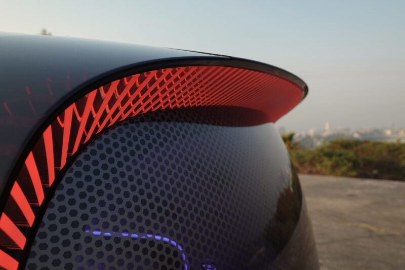 Close-up of the Mercedes-Benz Vision V concept’s rear end, showcasing an illuminated red taillight and hexagonal patterned surface, set against an outdoor backdrop.