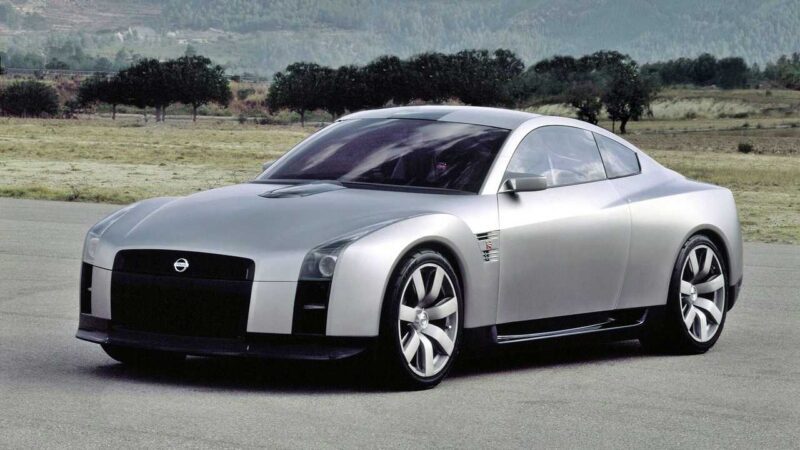 A silver Nissan R35 GT-R concept sports car is parked on a paved area with grass, trees, and distant hills in the background, capturing the end of an era and leaving us wondering what comes next for this iconic line.