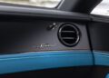 Close-up of a Bentley’s black dashboard featuring a circular air vent, the word "Speed" in chrome lettering, Ombre By Mulliner blue trim, and an exquisite paint finish.