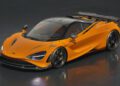 An orange sports car with black accents and a large rear wing is parked on a glossy dark surface.
