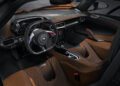 The interior of a modern McLaren sports car with orange and black seats, a digital dashboard, a central touchscreen, and a flat-bottomed steering wheel—perfect for Exotics On Broadway or the 750S Le Mans experience.