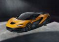 A bright orange McLaren 750S Le Mans supercar parked indoors on a concrete floor, featuring black accents and a sleek aerodynamic design.