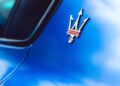 Close-up of a Maserati trident logo on the side of a blue GT2 Stradale, capturing the excitement of Car Week.