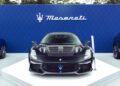 A matte black Maserati GT2 Stradale sports car is displayed on a white platform in front of a blue Maserati-branded backdrop.