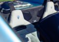 Close-up of two light-gray Maserati GT2 Stradale seats with blue trident logos, inside a convertible with the top down—perfect for Car Week showcases.