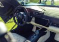 The interior of this modern sports car, inspired by the Maserati GT2 Stradale, features a suede-wrapped steering wheel, digital displays, control buttons, and a stylish mix of black and white upholstery perfect for Car Week.