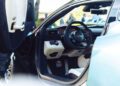 Close-up view of a Maserati sports car's open driver-side door, showcasing the GT2 Stradale steering wheel, dashboard, pedals, and part of the sleek exterior.