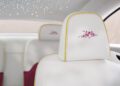 Primavera Inspired Car interior: white seats with pink floral embroidery on headrests, yellow trim, and star-like lights on the ceiling create a bespoke Rolls-Royce elegance.