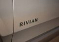Close-up of a vehicle's side panel displaying the word "RIVIAN" in capital letters, captured during Monterey Car Week’s exclusive auction event.