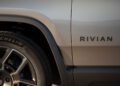 Close-up of a gray Rivian vehicle at Monterey Car Week, showing part of the wheel, tire with Michelin branding, and the Rivian logo on the side panel.