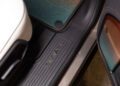 Close-up of a Rivian vehicle’s door sill featuring the brand name embossed on black trim, with a white seat and a colorful floor mat also visible—captured during Monterey Car Week ahead of its auction debut.