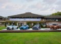 Four Bentley cars featuring the striking Ombre By Mulliner paint finish are displayed on an outdoor platform in front of a large building, with a green lawn and cloudy sky in the background.