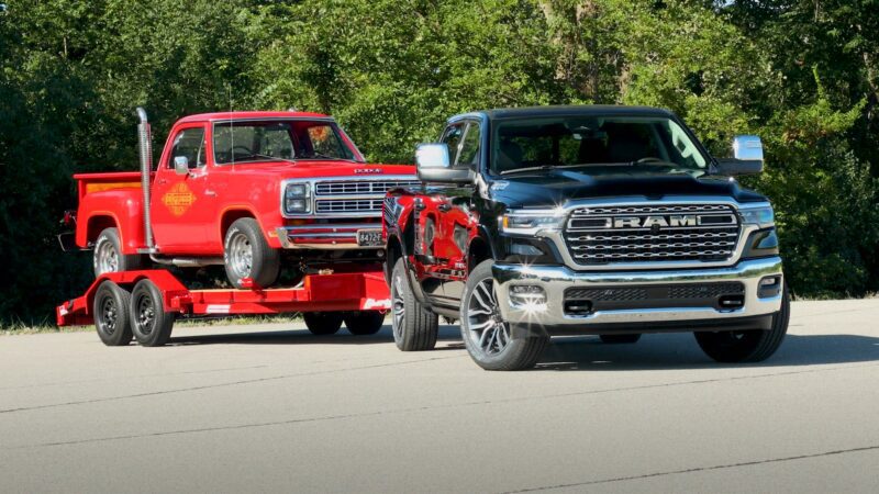 A red truck towing a black truck celebrates the return of power—The HEMI Is Back: First 2026 Ram 1500 V8s Roll Off the Line.