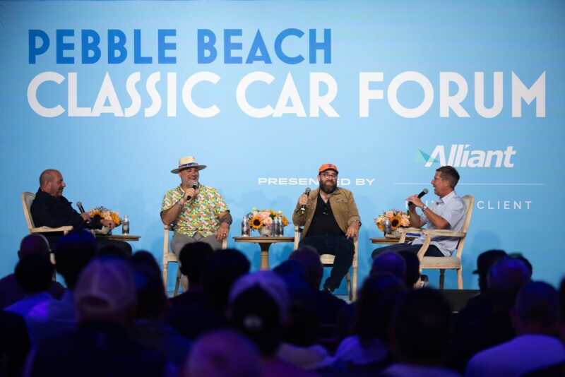 Four men sit on stage at the Pebble Beach Classic Car Forum during Monterey Car Week 2025, with microphones in hand, engaging in a lively discussion before an audience, presented by duPont REGISTRY.