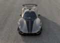 A top-down view of a grey Hennessey Venom F5 sports car with black racing stripes parked on a textured asphalt surface, showcasing its powerful 1,817 HP engine and manual transmission.