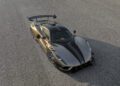 A sleek Hennessey Venom F5 in metallic gold with black racing stripes is parked on a textured paved surface, viewed from above at an angle—a true Revolution LF sports car.