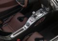 Close-up view of a luxury car interior showing the center console with metallic controls, 031HP manual gear shift, and brown leather seats.