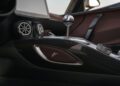 Close-up of a Hennessey Venom F5 manual hypercar's interior center console, showcasing a manual gear stick, two circular air vents, and carbon fiber trim.