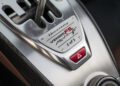 Close-up of a Hennessey Venom F5 gear selector plate for the Manual 2 model, featuring the iconic gated shifter slot and a striking red hazard light button.