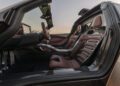 Interior view of the Hennessey Venom F5 with brown leather seats, advanced dashboard, and open butterfly doors, photographed at sunset—this 1,031HP sports car offers a luxurious manual driving experience.