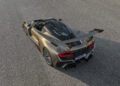 A metallic bronze Hennessey Venom F5 sports car with a large rear wing and red LED taillights, boasting 2,031HP, is parked on an asphalt surface, viewed from above and behind.