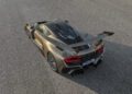 A Hennessey Venom F5 metallic sports car with a large rear wing is parked on an asphalt surface, viewed from above and behind.