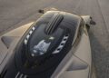 Top view of the Hennessey Venom F5, a high-performance 2,031HP sports car with a manual transmission. Its engine is visible through a glass cover, showcasing aerodynamic vents and sleek body detailing on an asphalt surface.
