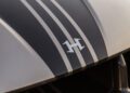 Close-up of a Hennessey Venom F5 hood featuring two black racing stripes with a stylized "H" logo in the center and bold 031HP accents.