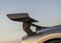 Close-up view of a black carbon fiber rear spoiler on a silver Hennessey Venom F5, the 2,031HP hypercar, set against a clear sky at sunset.