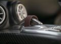 Close-up of the Hennessey Venom F5’s gear selector in Manual mode, with a brown leather strap, circular air vents, and carbon fiber trim elevating the luxury interior.
