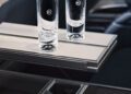 Two empty glass tumblers with a logo rest on a folded tray table inside a modern Range Rover SV, capturing refined comfort reminiscent of Monterey Car Week at Asilomar.