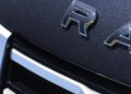 Close-up of the front grille and partial "RAM" badge on a dark-colored vehicle with a metallic finish, captured during Monterey Car Week near Asilomar.